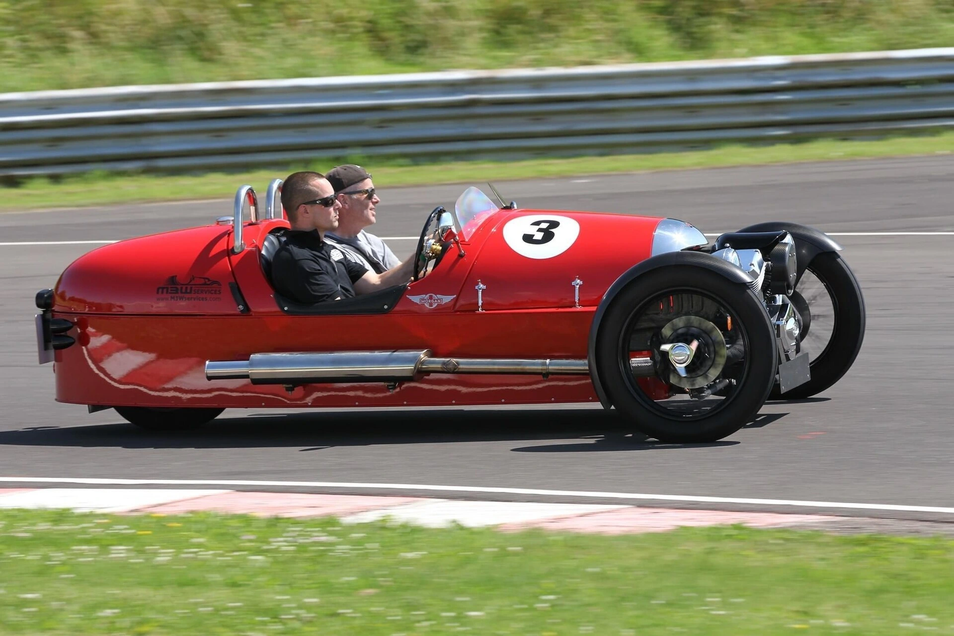 Red Morgan 3 Wheeler with race number 3 on track at speed