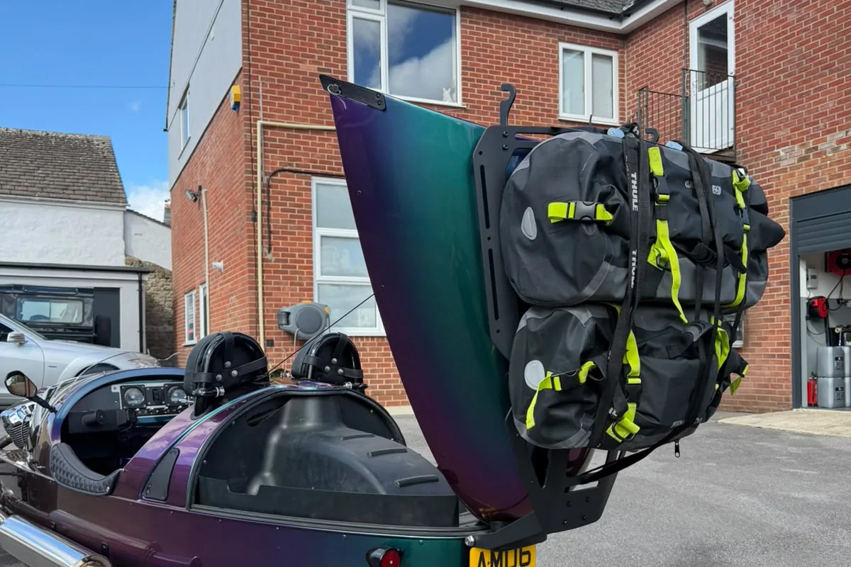 The boot lid of a Morgan 3 Wheeler raised with the luggage rack and bags still attached